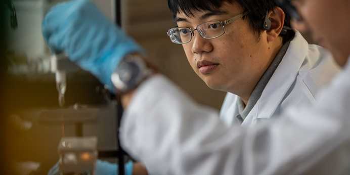 Photo of Case Western Reserve University students working in an engineering lab wearing lab coats