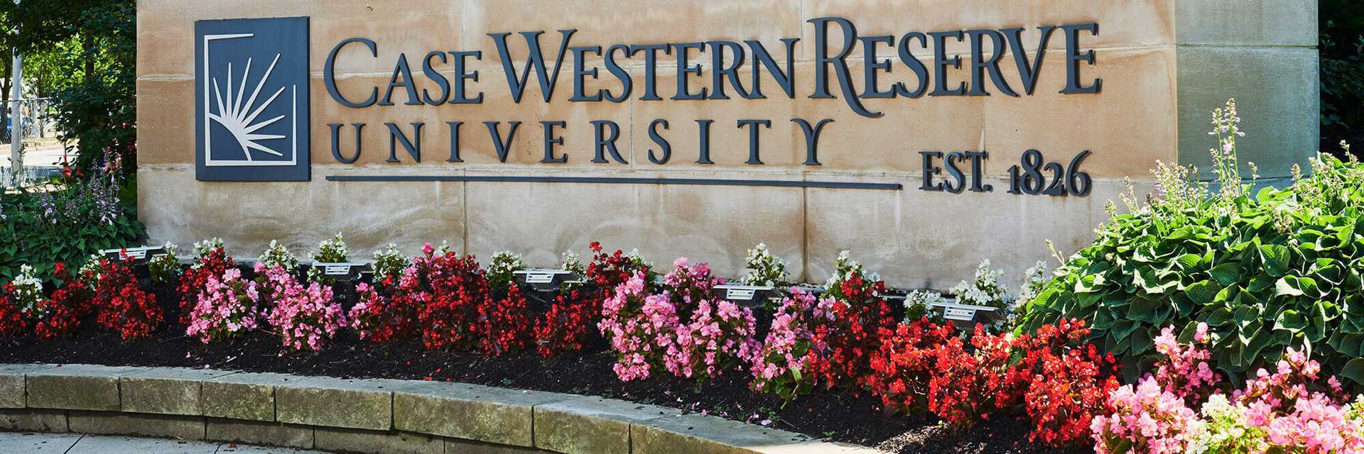 Photo of a stone sign on campus with the Case Western Reserve University logo, with flowers beneath