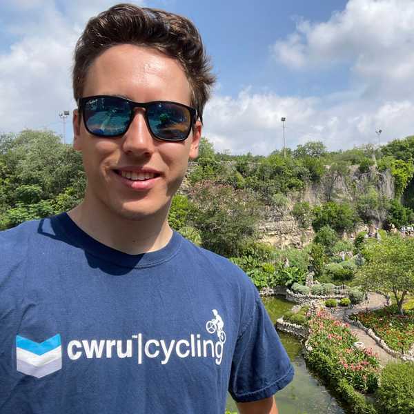 Fourth year CWRU student, Adam Kerkemeyer, posing in front of a picturesque garden.