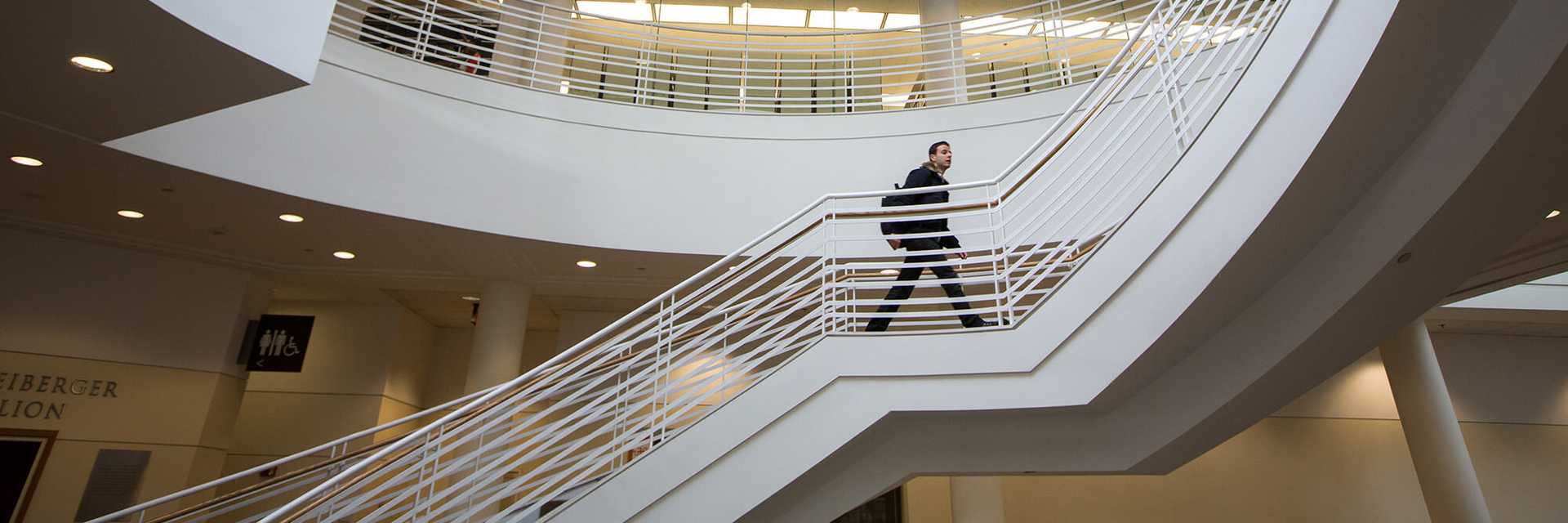 Photo of a Case Western Reserve University student walking up a spiral staircase in Kelvin Smith Library