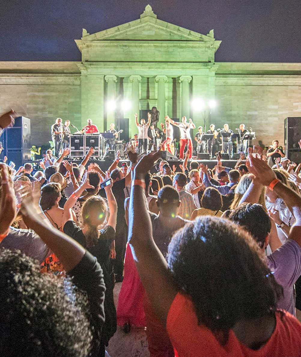 Photo of a crowd at an outdoor concert at Cleveland Museum of Art, with a band performing on stage in the background