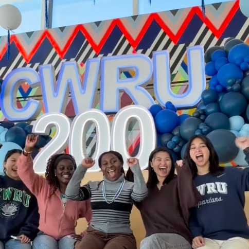 A group of students cheering in front of letters that read, “CWRU 200.”