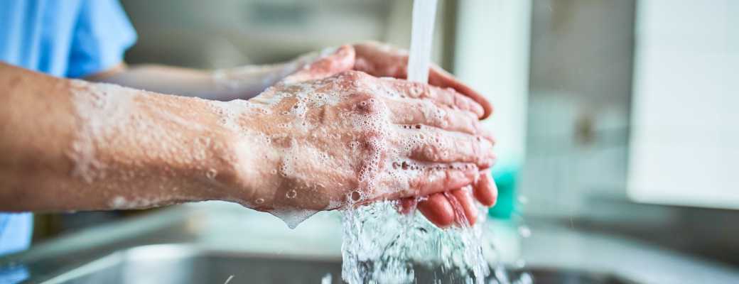 Person washing soapy hands under running water.