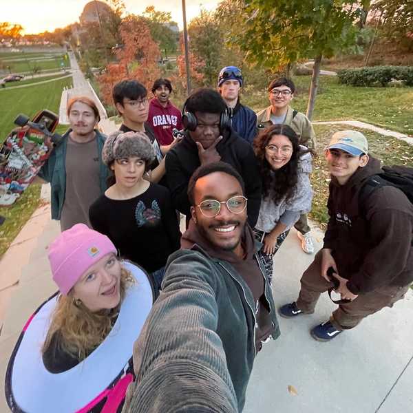 A group of 11 CWRU students pose together for a selfie outside on campus.