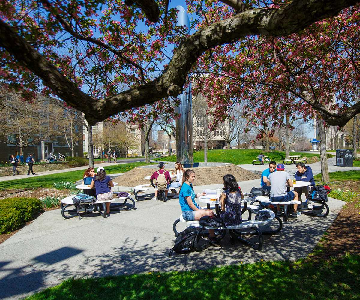 Photo of Case Western Reserve University students sitting at picnic tables with the Michelson-Morley fountain in the background