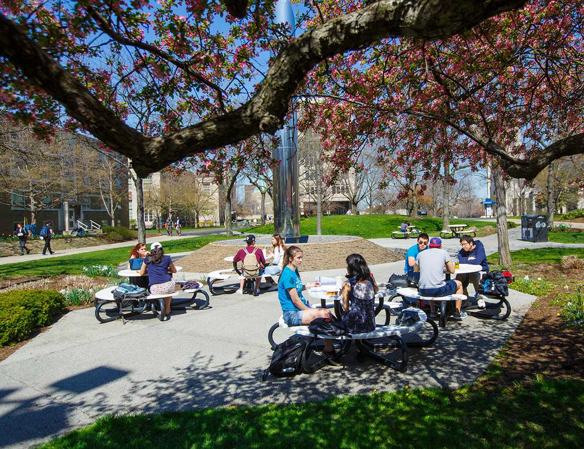 Photo of Case Western Reserve University students sitting at picnic tables with the Michelson-Morley fountain in the background