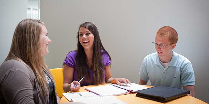 Three students sitting at a table laughing