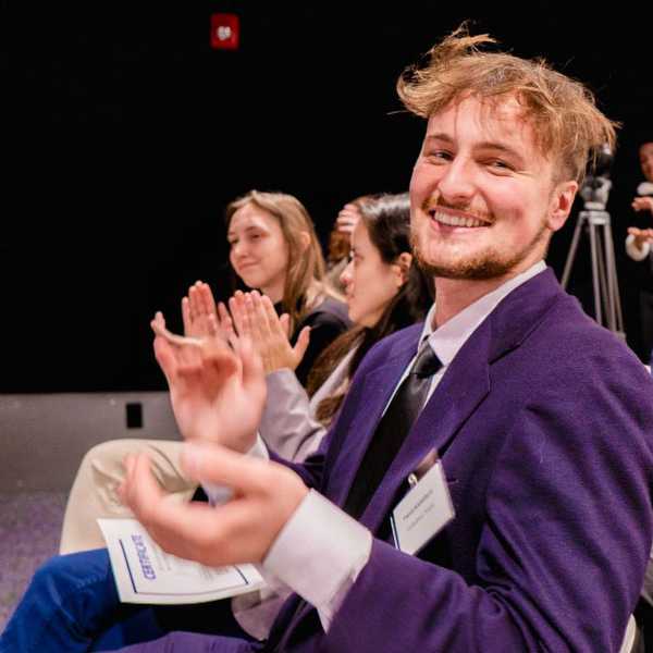 One student seated while smiling and clapping at the 2024 Morgenthaler-Pavey Startup Competition.