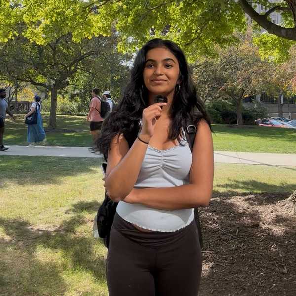 CWRU student posing with microphone under a tree on Case Quad.