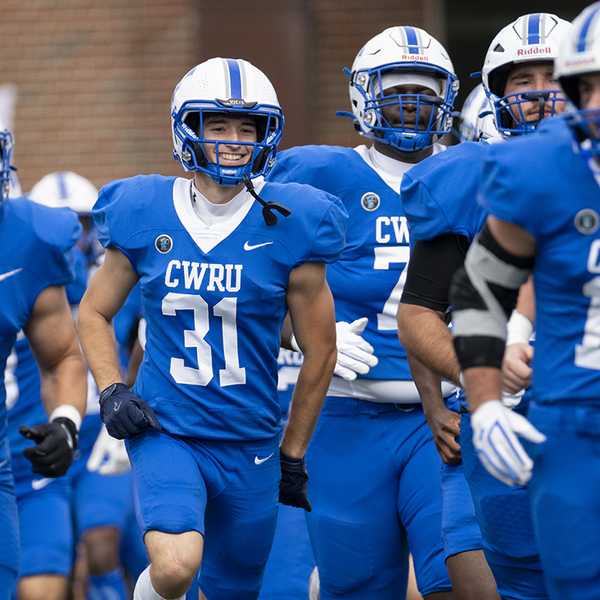 A group of Spartan football players running onto the field.