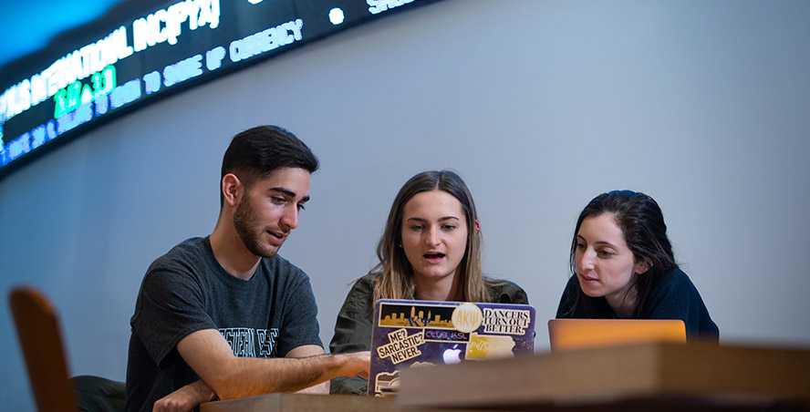 Photo of three Case Western Reserve University students sitting at a table looking at a laptop