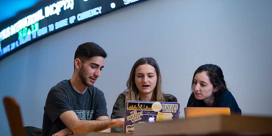 Photo of three Case Western Reserve University students sitting at a table looking at a laptop