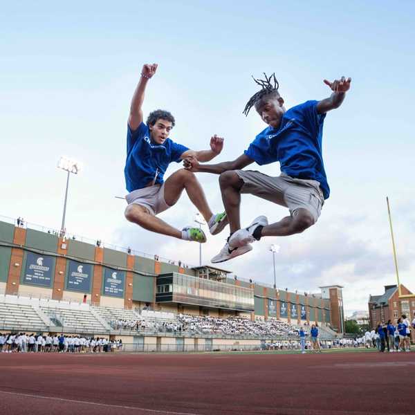 Two students jump in the air at DiSanto Field.