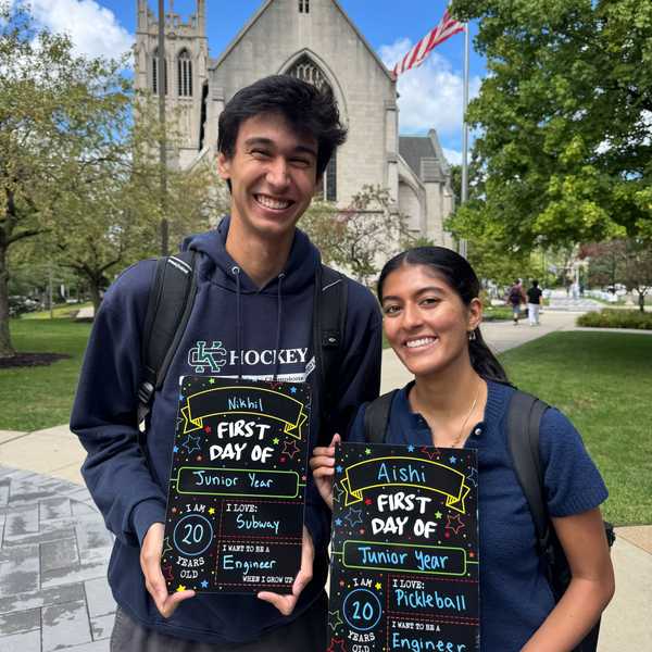 Two CWRU students pose holding first-day-of-school picture boards with written answers on Case Quad.