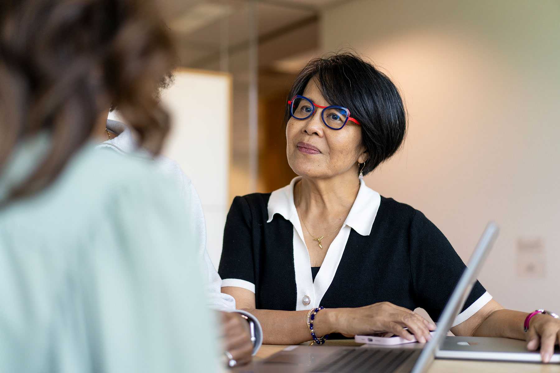 Photo of a woman wearing glasses at a desk listening closely