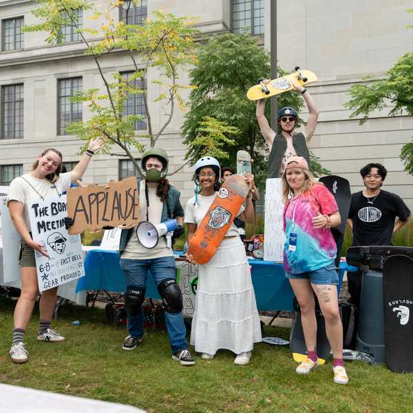 Seven CWRU students pose with skateboards at the Fall Student Activities Fair while tabling for their on-campus skateboarding club, “The Board Meeting.”