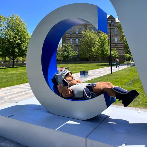 Mascot Spartie lounging on a CWRU sign on campus.