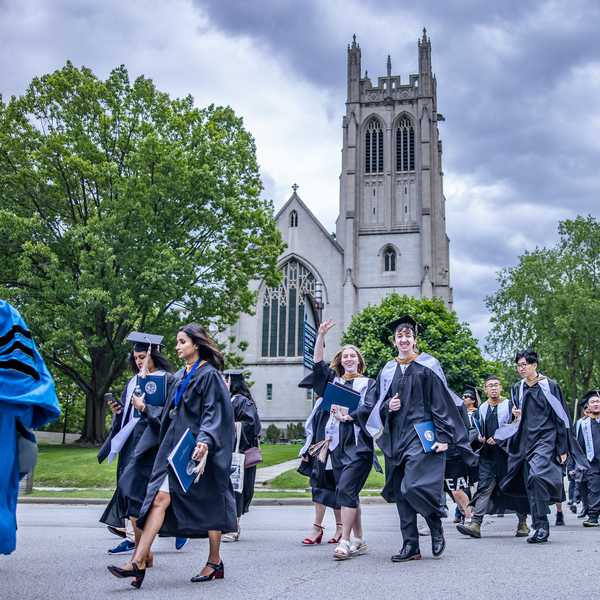 A large group of graduating students crossing Euclid Avenue in front of Amasa Stone Chapel.