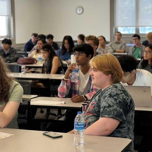 A group of CWRU students in a lecture hall taking notes and listening to the speaker.