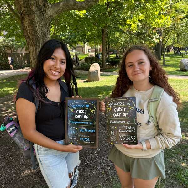 College students on Case Quad pose holding first-day-of-school picture boards with written answers.