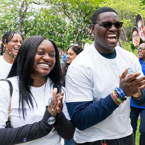 Two students smiling and clapping with bubbles floating behind them on Case Quad.