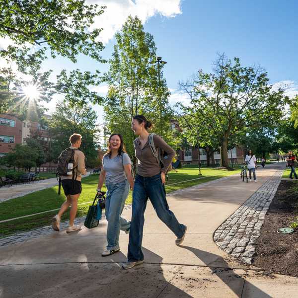 Three students walking through campus on a sunny day.