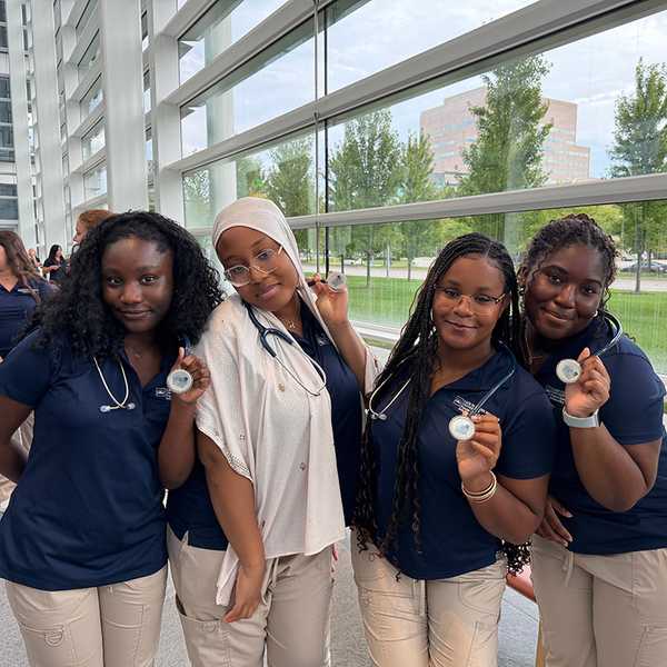 A group of four nursing students posing with their stethoscopes.
