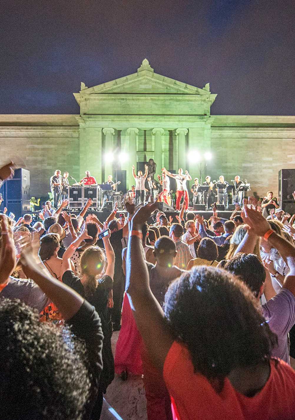 Photo of a crowd at an outdoor concert at Cleveland Museum of Art, with a band performing on stage in the background
