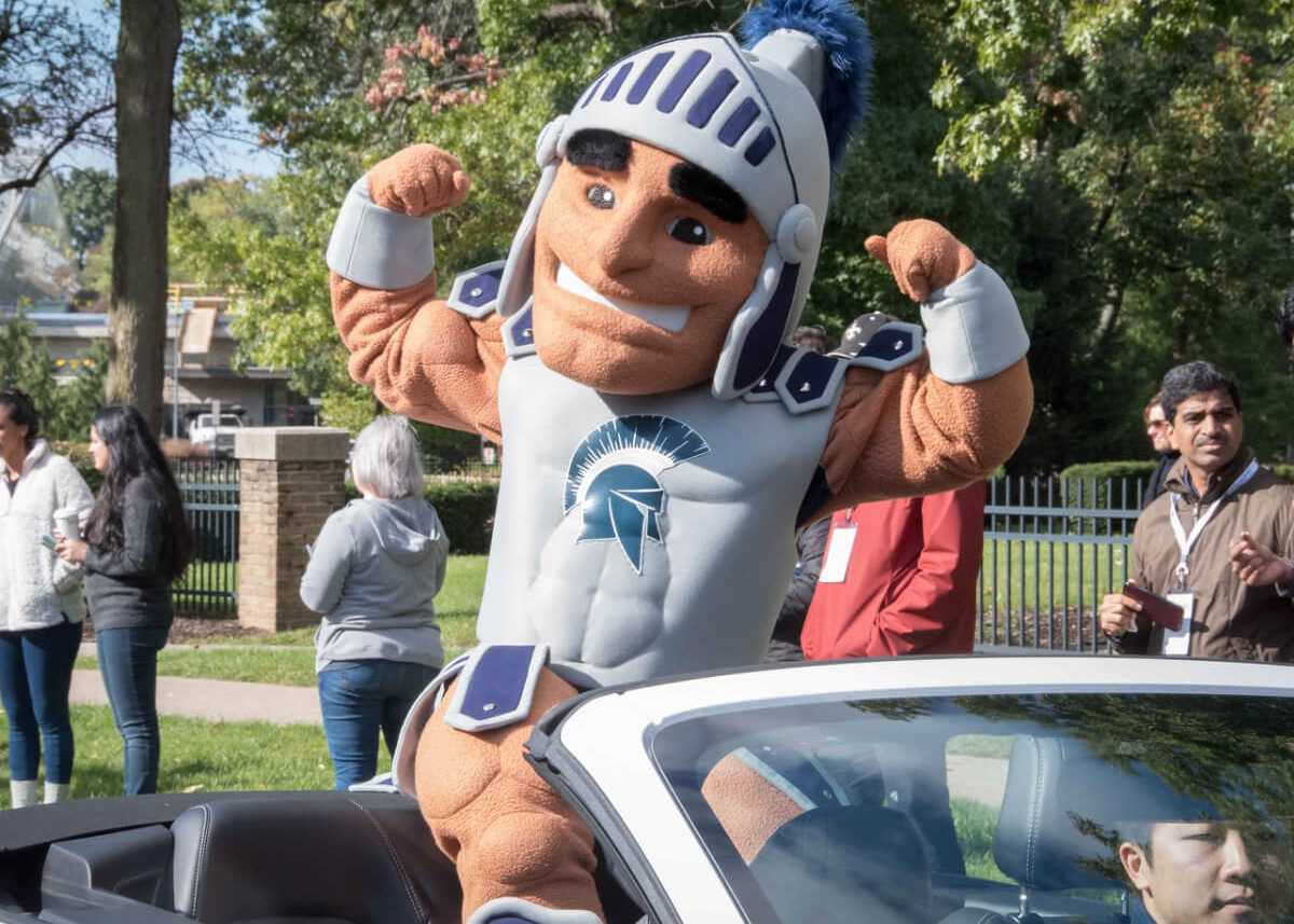 Photo of Case Western Reserve University Spartan mascot, Spartie, flexing muscles while riding in a car in the homecoming parade