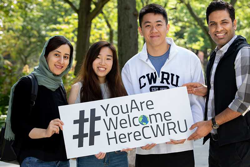 Photo of four Case Western Reserve University students holding a sign that says “#YouAreWelcomeHereCWRU”
