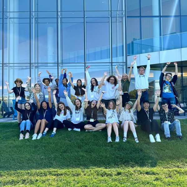 Twenty CWRU orientation leaders pose with their arms up in front of Tinkham Veale University Center.