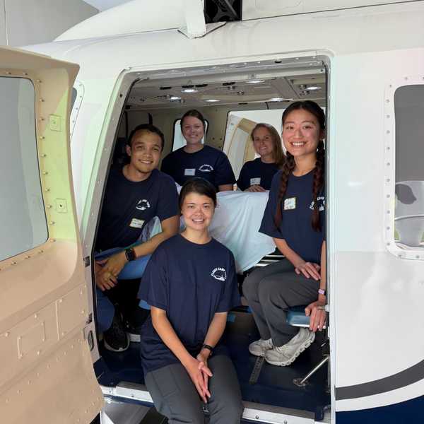 Five nurses pose in Frances Payne Bolton School of Nursing’s helicopter flight simulator.