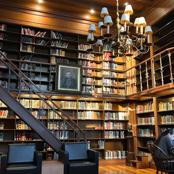 An interior photo of Ford Library with a wood-framed wall of shelves filled with books and a large light fixture.