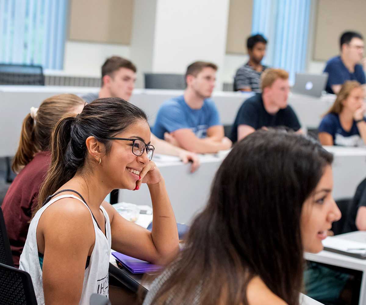 Photo of Case Western Reserve University students sitting in a classroom, with a focus on one in the foreground smiling