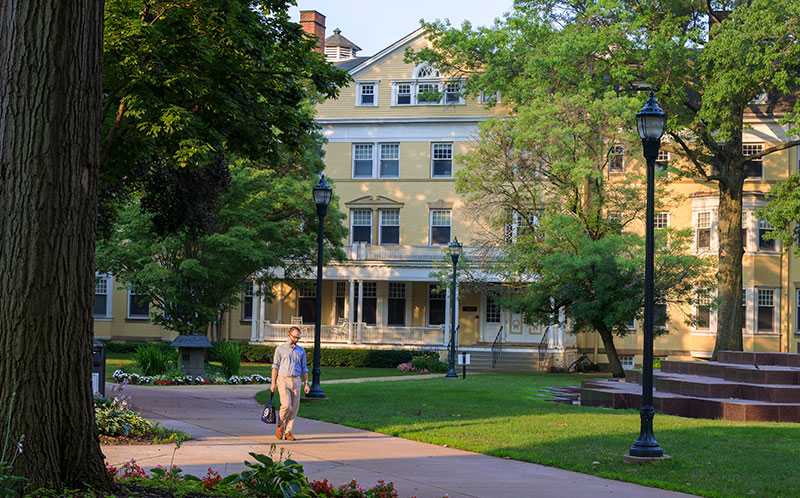 Photo of Guilford House on Mather Quad at Case Western Reserve University, with a student walking in front on sidewalk