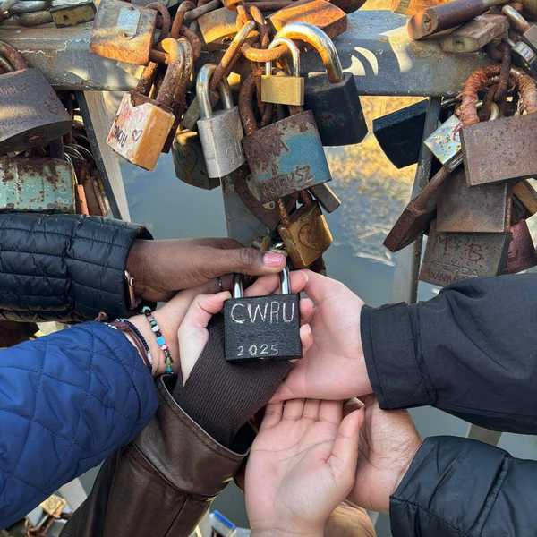 A group of six hands holding a lock with “CWRU” written on it.