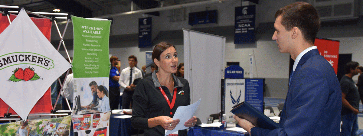 Corporate recruiter speaking to a Case Western Reserve University student at a career fair booth