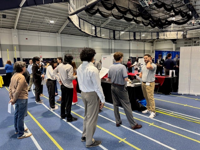 Students standing in line at career fair employer table