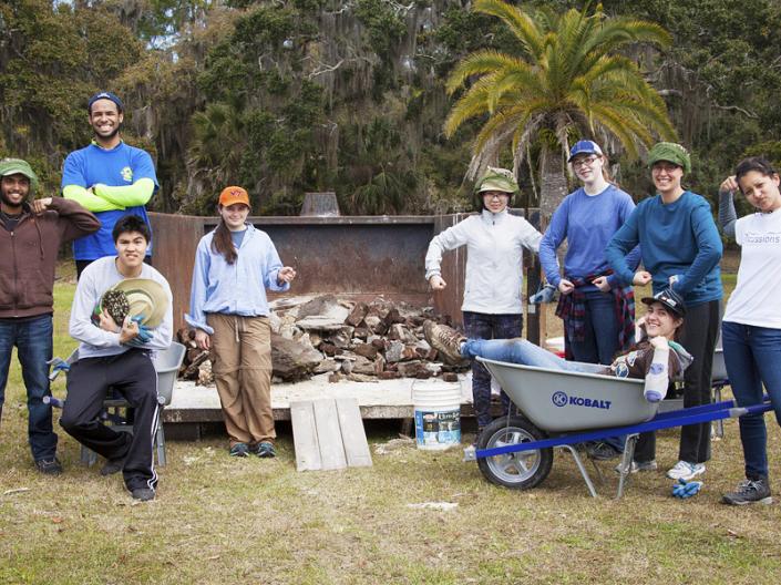 Students in work clothes cleaning up debris