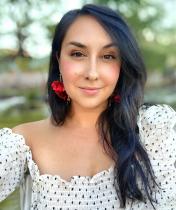 Headshot of Samantha Cocco, a white woman with dark hair, a white polka dot shirt, and bright red earrings