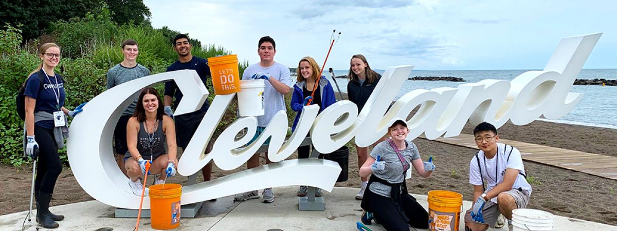 Students gathered around a Cleveland script sign