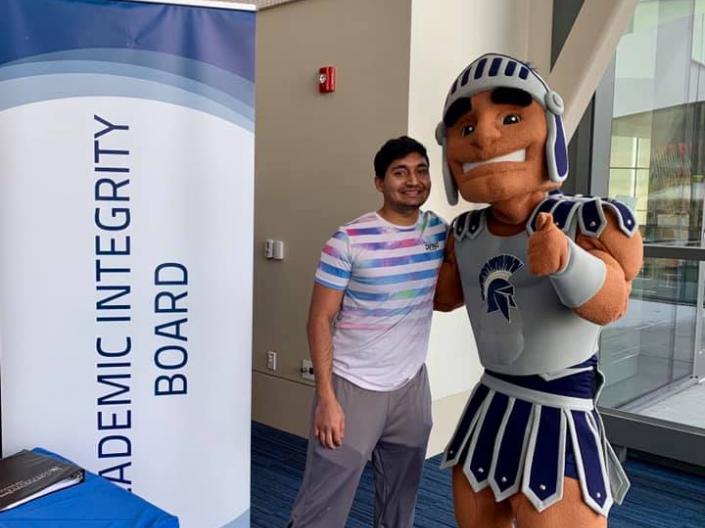 Student and Spartie next to an Academic Integrity Board sign