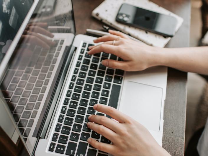 Closeup of a person's hands typing on a laptop keyboard