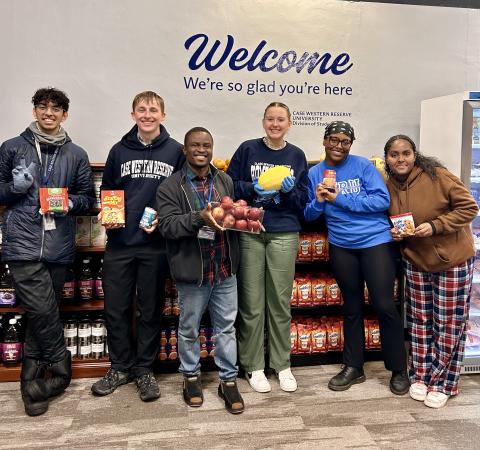 Seven student workers standing in front of a Welcome, We're So Glad You're Here sign