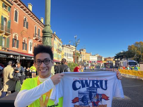 CWRU student in Verona, Italy holding vintage CWRU t-shirt after racing a marathon