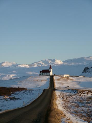 Photo of road in Iceland leading to snow-covered church.