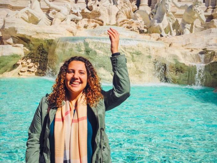 A student throws a coin into a fountain while studying abroad