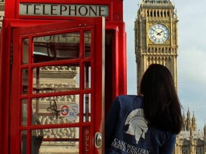 student looks at Tower of London from a red phone booth