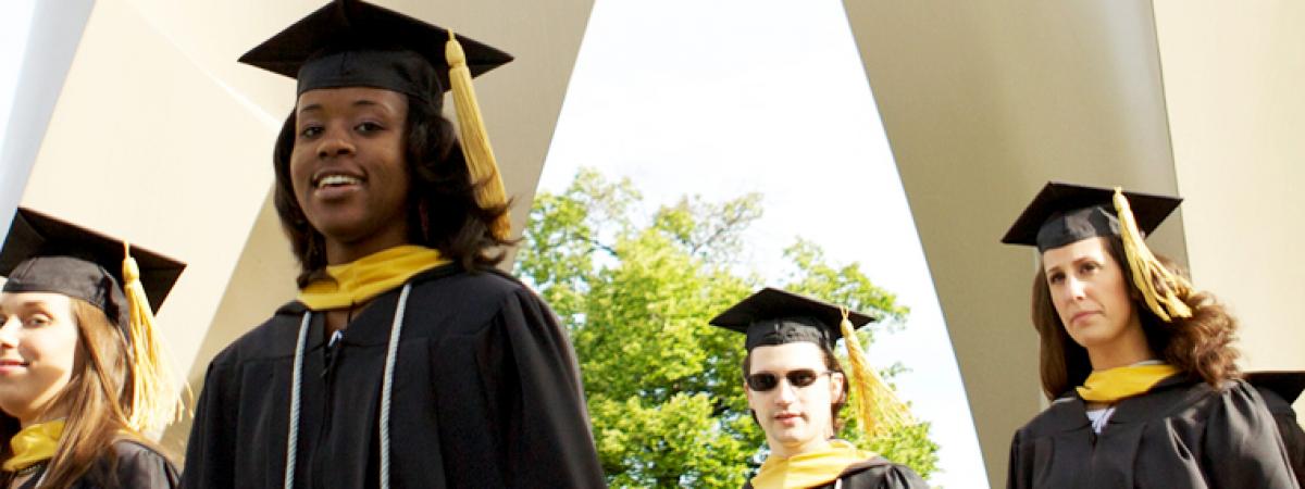 Students walking outside in graduation caps and gowns