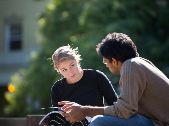Two students talking and studying outside